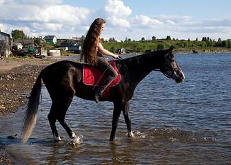 Image showing A girl with flowing hair on a black horse