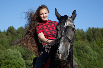 Image showing Beautiful girl with brown hair on a black horse