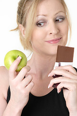 Image showing woman deciding whether to eat apple or chocolate