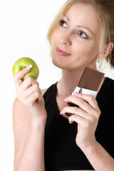 Image showing woman deciding whether to eat apple or chocolate