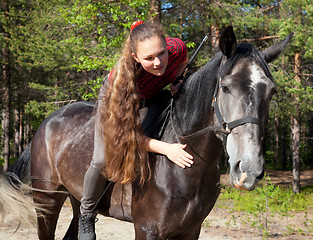 Image showing A girl with her hair stroking horse