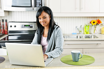 Image showing Woman using computer in kitchen