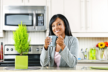 Image showing Woman in kitchen with coffee cup