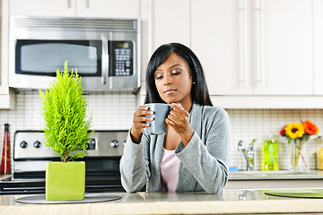 Image showing Woman in kitchen with coffee cup