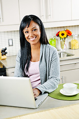 Image showing Woman using computer in kitchen