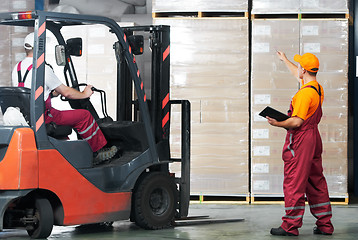 Image showing warehouse works (forklift and workers)