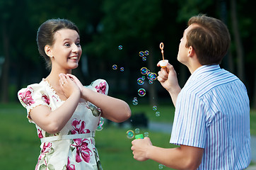 Image showing happy couple blowing soap bubbles