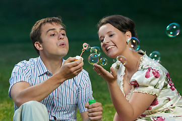 Image showing happy couple blowing soap bubbles