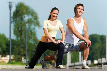 Image showing Young man and woman doing stretching exercises