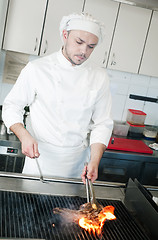 Image showing chef frying beef steak on grill with fire