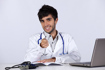 Image showing frendly young doctor working with his laptop