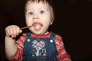 Image showing girl licks a silver spoon