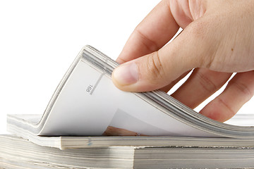 Image showing hand browsing through stack of magazines