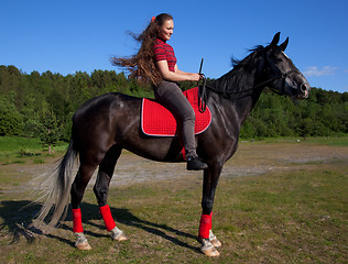 Image showing Beautiful girl with brown hair on a black horse