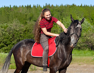 Image showing A girl with her hair stroking horse