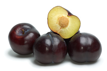 Image showing Some whole plums and one half