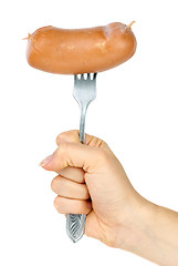 Image showing Hand holding sausage on fork. Isolated on the white background