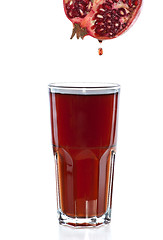 Image showing Half of pomegranate with drop and glass with juice