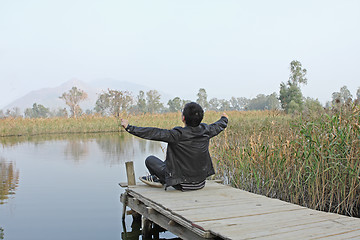 Image showing Man resting on a pontoon by a lake 