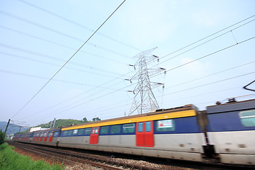 Image showing passenger trains in motion and power tower on background 