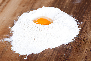 Image showing broken egg on flour
