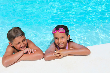 Image showing Happy children,  girl and boy, relaxing on the side of a swimmin