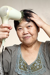 Image showing female drying her hairs with drier