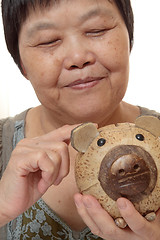 Image showing woman putting coins in small piggy bank. Selective focus, Copy s