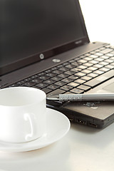 Image showing A cup of coffee and a pen on a laptop 