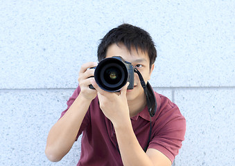 Image showing young teenage photographer taking a photo with his DSLR camera. 