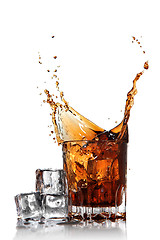 Image showing splash of cola in glass with ice cubes isolated on white