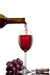 Image showing Red wine pouring into glass with grape isolated on white