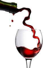 Image showing Pouring red wine in glass goblet isolated on white