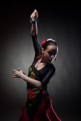 Image showing young woman dancing flamenco with castanets on black