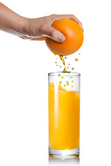 Image showing squeezing orange juice pouring into glass isolated on white