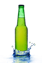 Image showing Green beer bottle with water drops and splash isolated on white