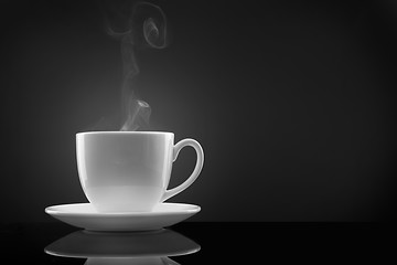 Image showing white cup with hot liquid and steam on black