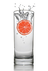 Image showing Grapefruit dropped into water glass with splash isolated on whit