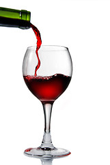 Image showing Pouring red wine in goblet isolated on white