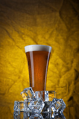 Image showing Beer in glass with ice cubes on yellow background