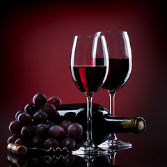Image showing Wine in glasses with grape and bottle on red