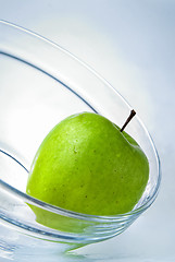 Image showing green apple in glass plate on blue background