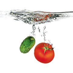 Image showing red tomato and green cucumber dropped into water isolated on whi