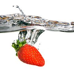 Image showing Fresh strawberry dropped into water with splash isolated on whit