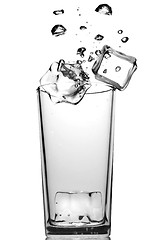 Image showing ice cubes dropped into glass with bubbles isolated on white