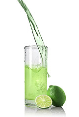 Image showing green juice with lime pouring into glass isolated on white