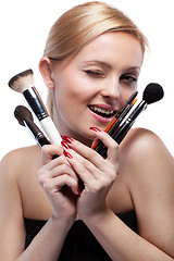 Image showing Young smiling woman with make up brushes isolated on white