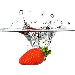 Image showing Fresh strawberry dropped into water with splash isolated on whit