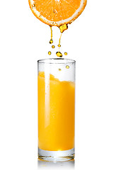Image showing Pouring orange juice from orange into the glass isolated on whit