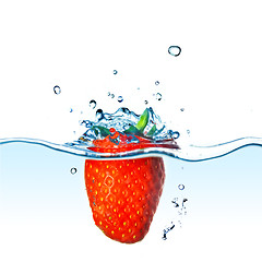 Image showing Fresh strawberry dropped into blue water with splash isolated on